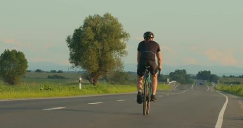 A Cyclist is Riding Along the Highway at a Slow Pace