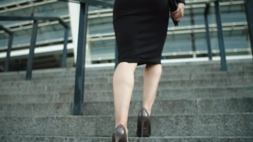 Back View Unrecognized Woman Legs Going Upstairs. Woman Looking Away at Street