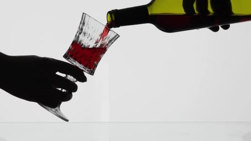 Silhouette of Hand Pouring Red Wine into Glass