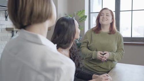 Charmante rothaarige Frau in Übergröße hört Freund zu, der vorne spricht und lächelt
