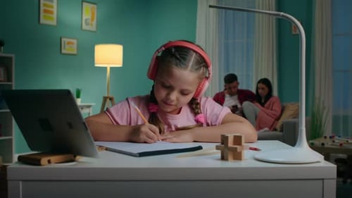 Girl Studies at Desk as Parents Relax Nearby