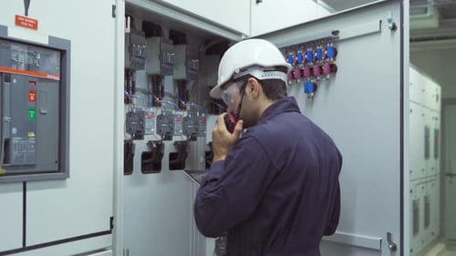Electrical Engineer Inspecting Electrical Panel Using Radio