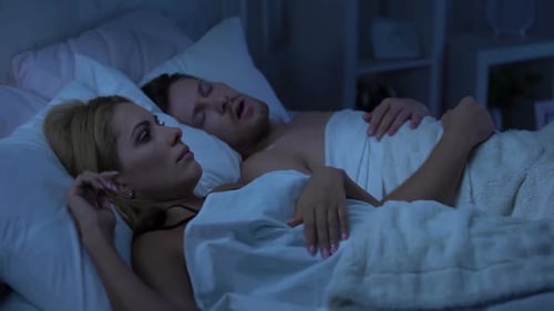 Femme au lit avec son mari, insomnie à cause du ronflement, déviation de la cloison nasale