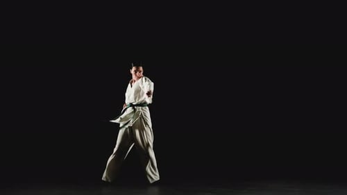 Woman Performing Karate Moves in Dark Studio