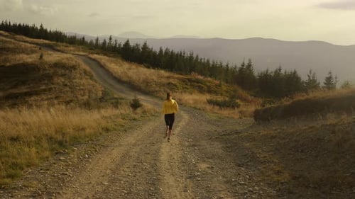 Female Athlete Running on Road in Mountains