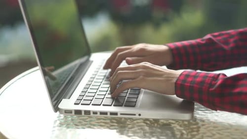 Hands Typing on a Laptop Outside on Glass Table