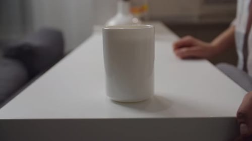 Unerkennbare weibliche Tasse, die von Hand weggenommen wird, wenn sie drinnen von der Aufnahme weggenommen wird