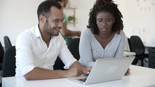 Colleagues Discussing Work on a Laptop in Office