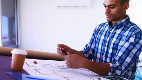 Male architect working on blueprint over drafting table 4k