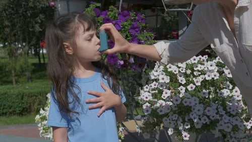 Girl Receives Asthma Inhaler by Flower Bed