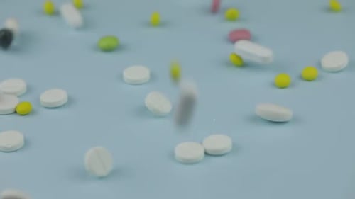 Pills Falling on Light Blue Surface