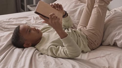 African American Schoolboy Playing Games on Digital Tablet