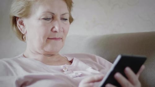 Woman Using Tablet While Relaxing on Couch