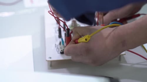 Hands Working with Wires on Circuit Board