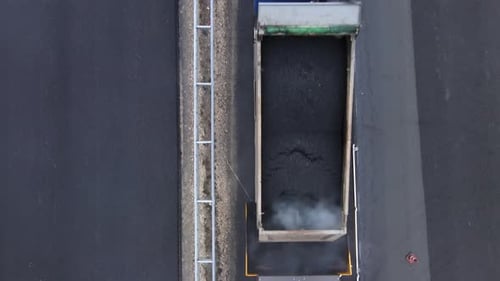 A top view of roadwork phase. Freshly prepared asphalt mix is poured into paver