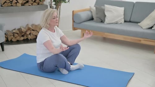 Senior Woman Meditating on Yoga Mat in Living Room