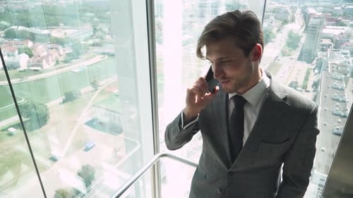Young Adult Businessman Talking on Phone in Elevator