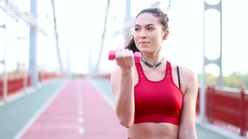 Woman Exercising Biceps on Urban Pedestrian Bridge