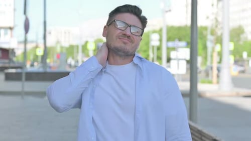 Man Rubbing His Neck in City Street