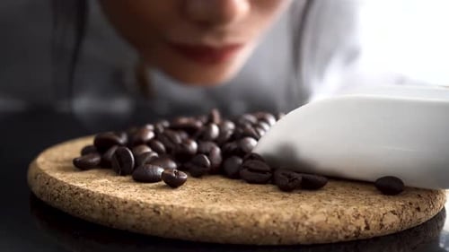 Woman Smelling Roasted Coffee Beans with White Scoop