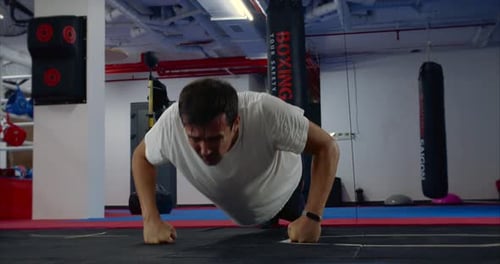 A Boxer Performs a Bench Press Pushup Exercises From the Floor in the Gym