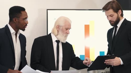 Businessmen Reviewing Corporate Data in Office