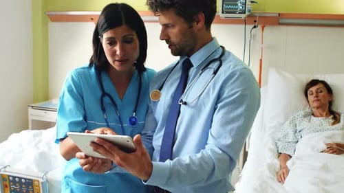 Doctors and Nurse Reviewing Tablet in Hospital Room