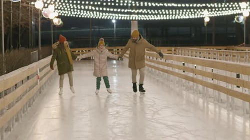 People Ice Skating at Night on Outdoor Rink