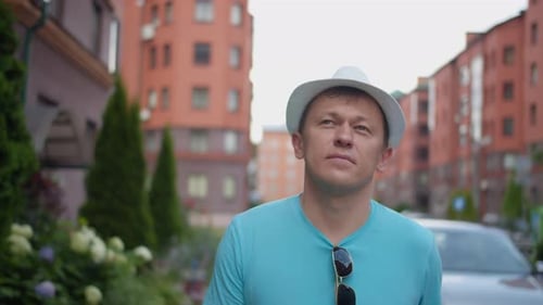 Young man walking around the city wearing white hat tracking with camera
