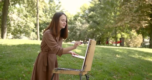 Girl Artist Paints on an Easel in the Park