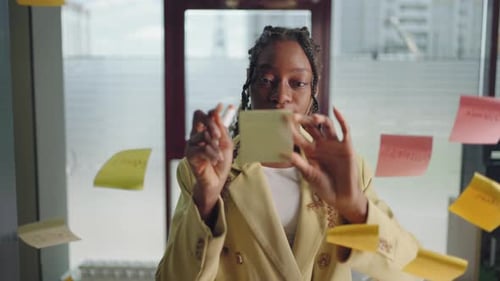 Woman Writing on Sticky Note in an Office