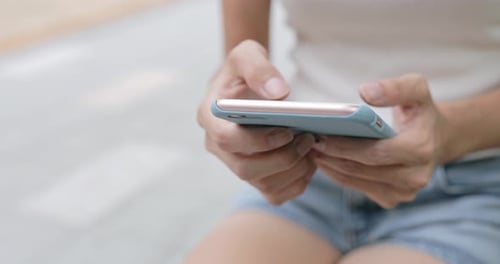 Woman Scrolling on Cell Phone in Urban Setting