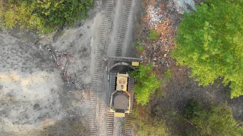 Top Aerial View on Tracked Bulldozer Rides on Sandy Road at Construction Site