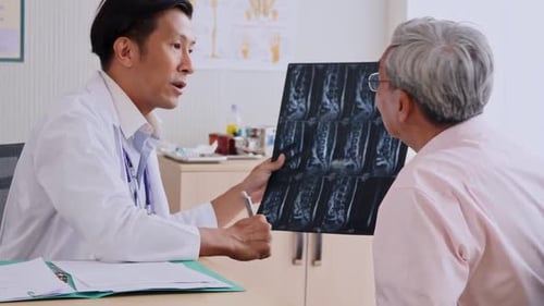 Expert doctor examining and explaining x-ray film to patient