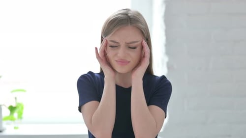 Woman Massaging Temples with Headache Indoors
