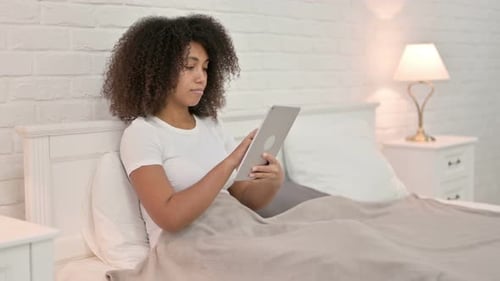 Woman Relaxes with Tablet in Bright Bedroom
