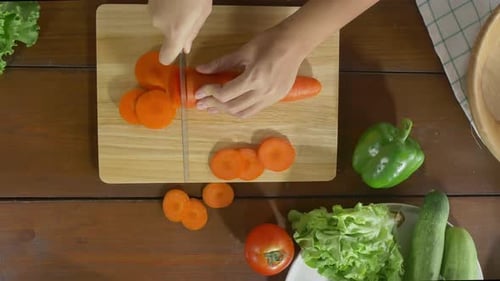 Chefin zubereitet Salat, gesundes Essen und hackt Karotten auf einem Schneidebrett in der Küche.