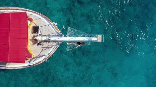 Une fille en bikini s'allonge dans un hamac sur la proue d'un yacht sur fond de mer