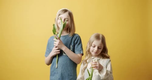 Two Young Girls Holding Yellow Tulips