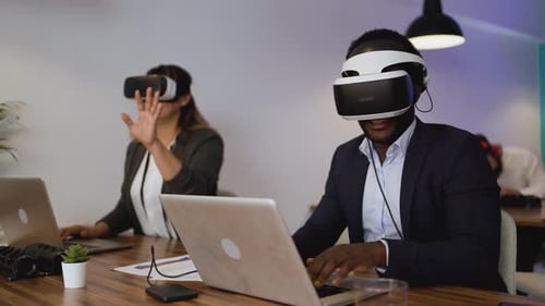Adults Use VR Headsets at Office Desks