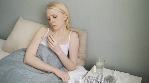Woman Lying in Bed Taking Temperature, Feeling Sick