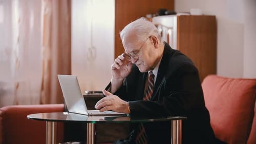 Senior Man Diligently Typing on Laptop at Home