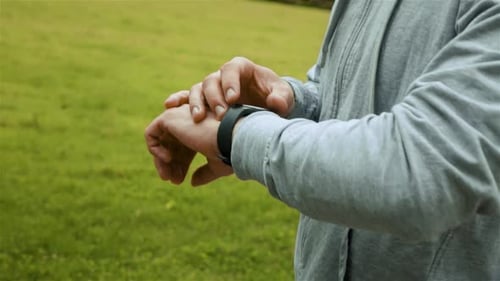 Man Using Smart Watch Outdoors on Grassy Field