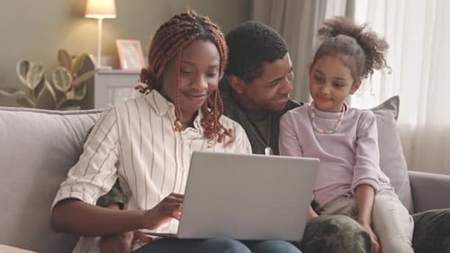 Smiling Family Video Chatting on Laptop at Home