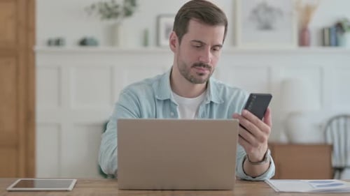 Adult Man Using Cellphone at Desk Indoors