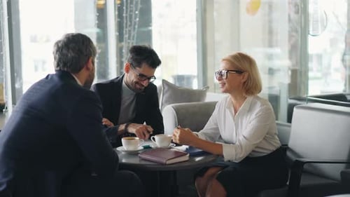 Cheerful Coworkers in Formal Clothing Talking Smiling in Cafe During Lunch Break