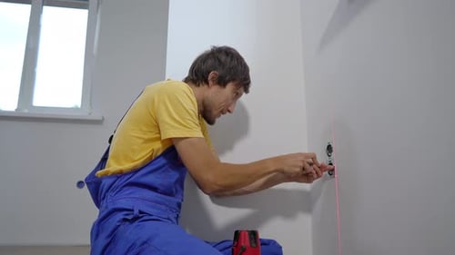 An Electrician Installs an Electric Socket Outlet Into Wall