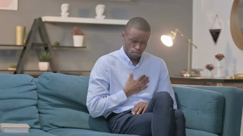Hombre africano tosiendo sentado en el sofá