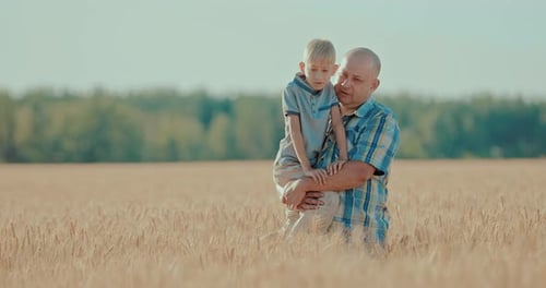 Happy Son with His Dad in His Arms Walking Around the Field