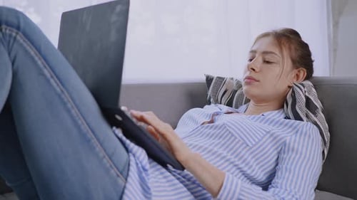 Woman Relaxes on Couch While Using Laptop